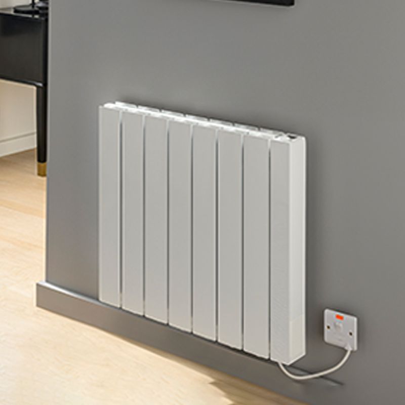 Modern white electric radiator wall-mounted in a contemporary room with plug socket.