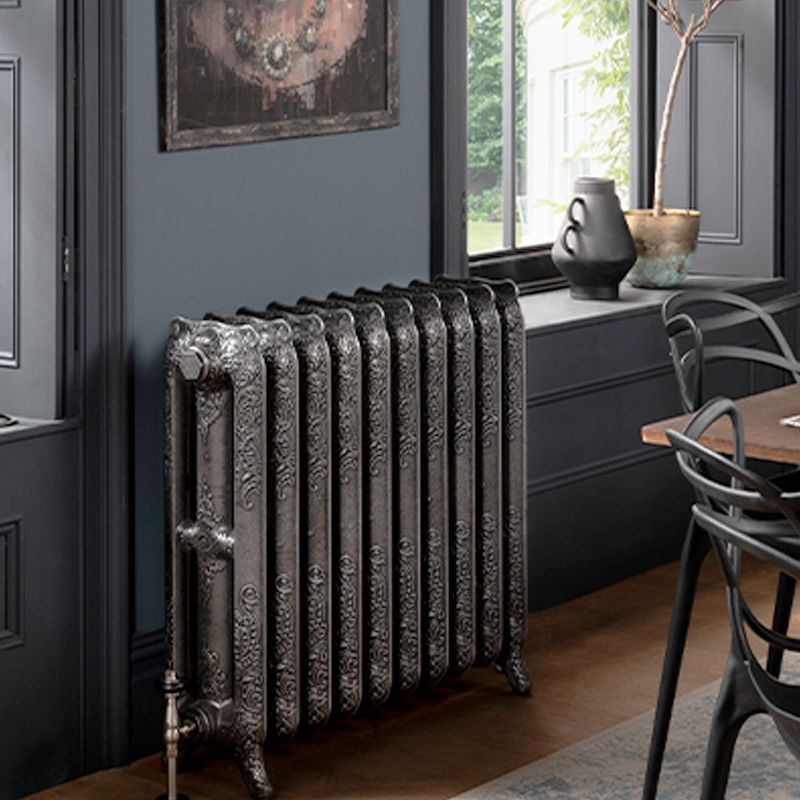 Traditional cast iron radiator with ornate detailing in a stylish dining room setting.