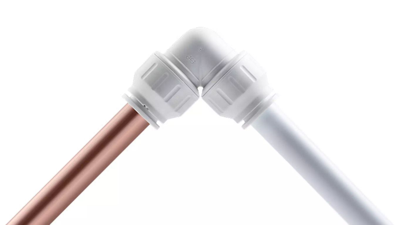 JG Speedfit push-fit elbow connector joining copper and plastic pipework on a white background.