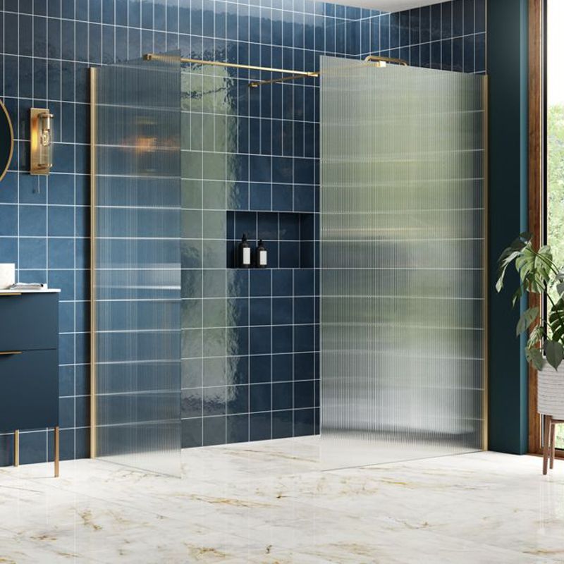 Modern walk-in shower with fluted glass panels, brushed brass frame, and navy blue tiled walls in a luxury bathroom.